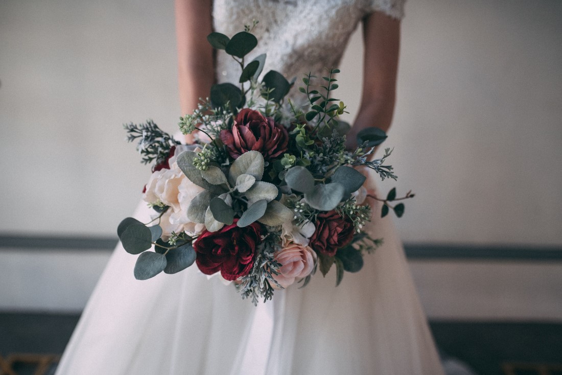 bride holds bouquet of roses and greenery