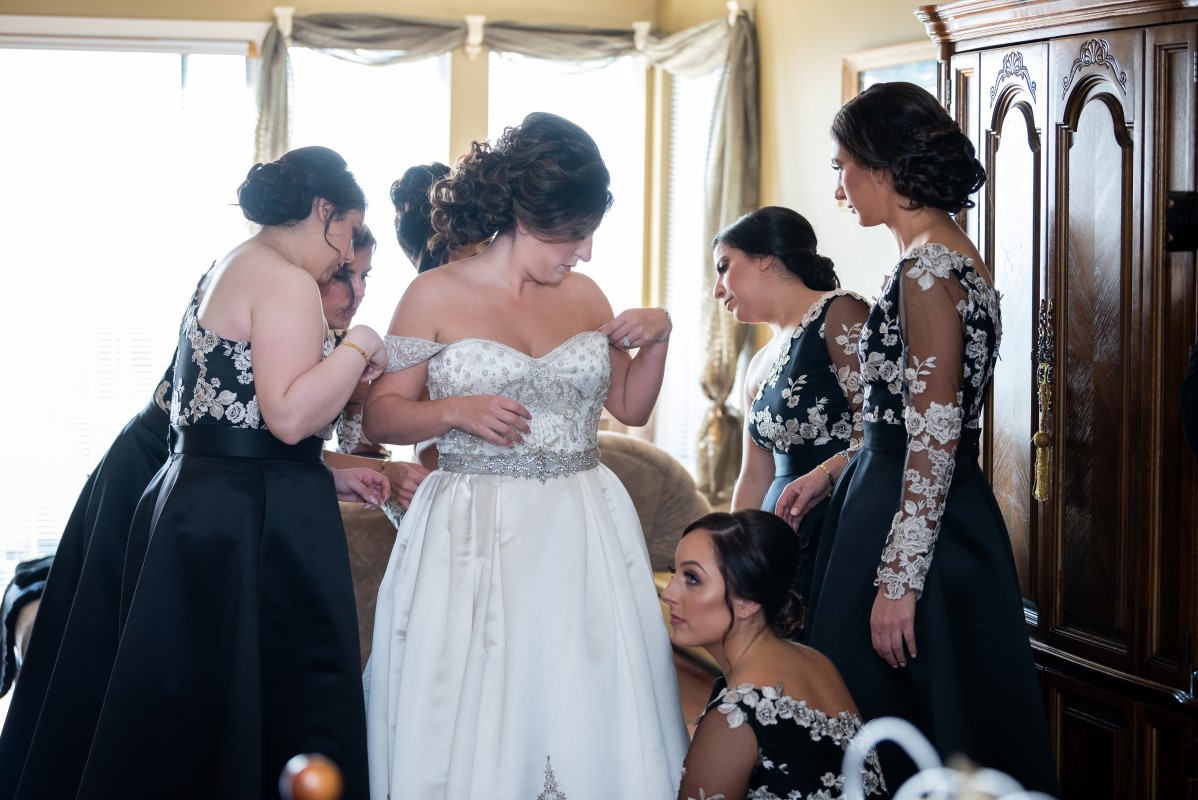 Bridesmaids help Vancouver bride put on her wedding gown