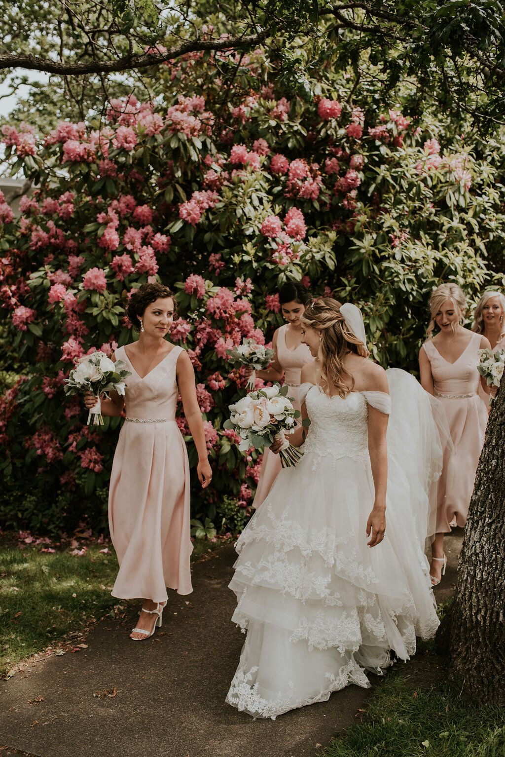 Romantic Bride Tribe walk along pink flowers on path