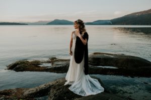 Bride on Beach wearing lace gown and brown fur stole during sunset on Vancouver Island
