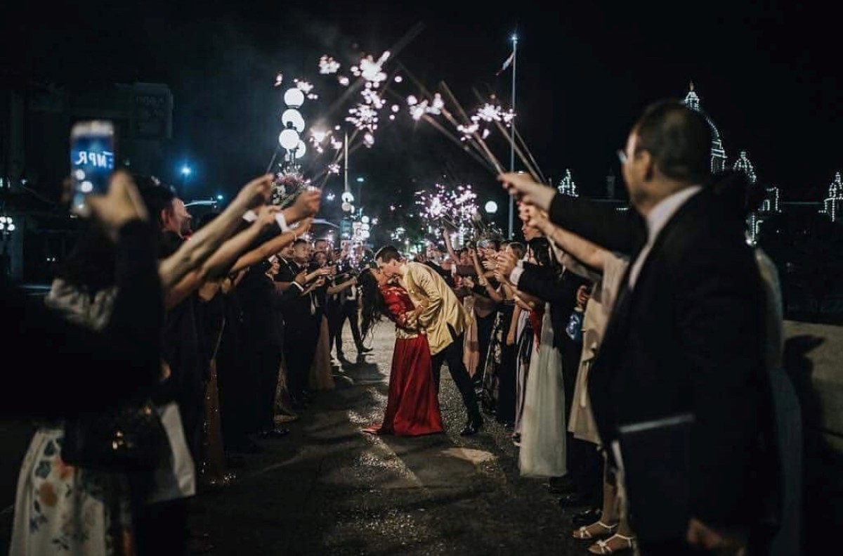 Newlyweds kiss as a guests hold sparklers around them