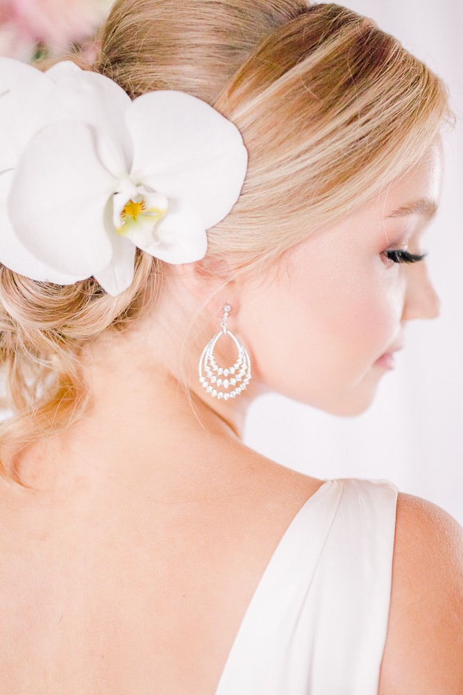 Bride with white orchid in chignon by Paragon Makeup and drop earrings by Luxia Jewelry in Vancouver