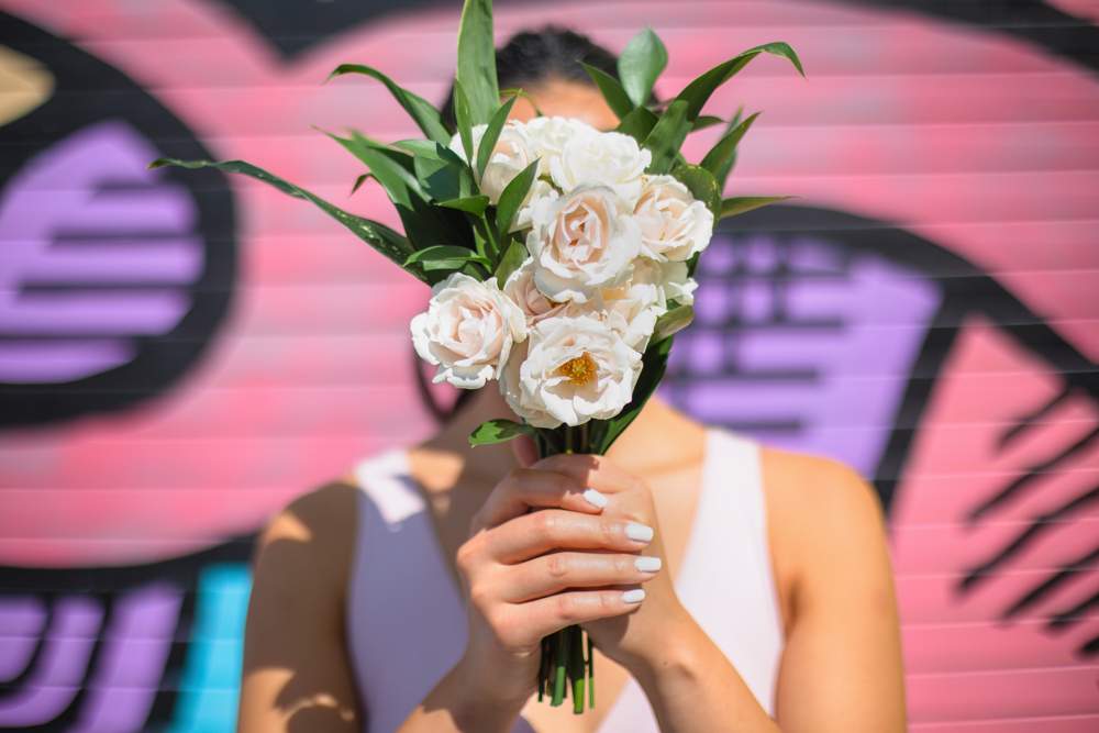 City Chic Bride holds bouquet in front of her face