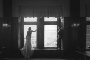 Bride wearing Shades of White Bridal looks out Fairmont Empress Window on Vancouver Island