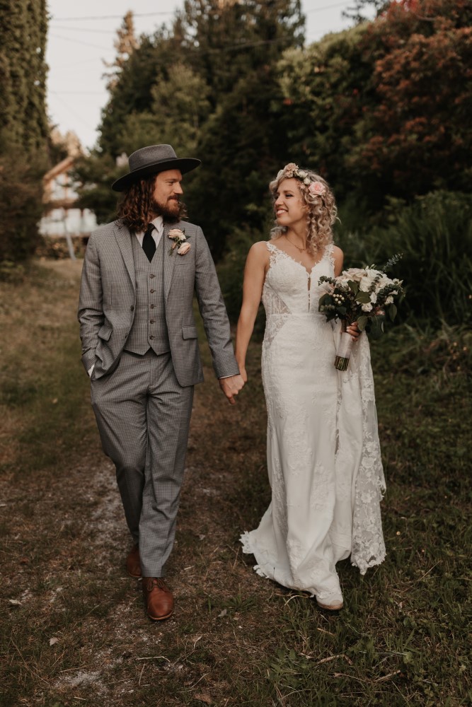 West Coast Weddings Magazine Indochino suit Martina Liana Gown bride and groom walking through forest holding hands floral designs by Coastal Weddings & Events