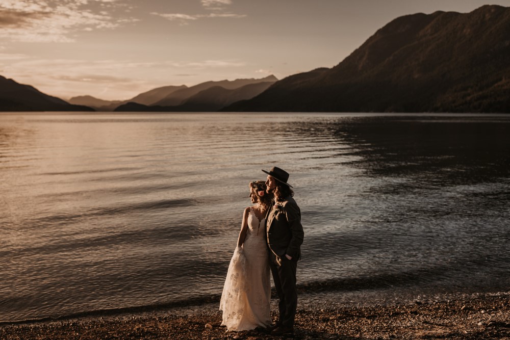 Golden Hour Elopement on the beach by the lake with mountains staring off into the distance Jennifer Picard