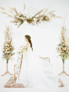 Bride in Vera Wang in white space with floral arrangements around her