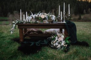 Low Sweetheart Wedding Table in Field on Vancouver Island covered in candles and white roses