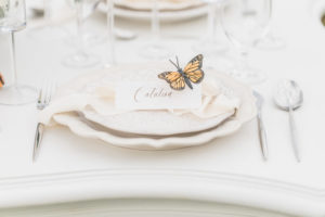 Monarch butterfly on edge of white place on wedding decor table in Vancouver