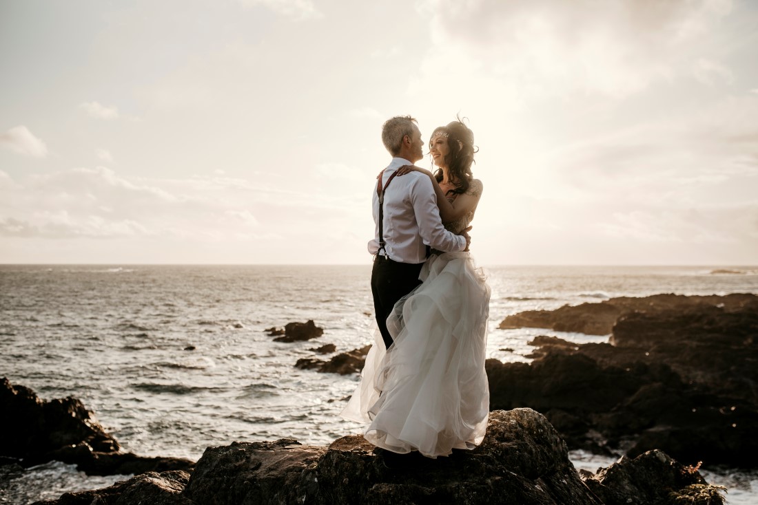 Bride and groom hold each other while looking out over the ocean on Vancouver Island