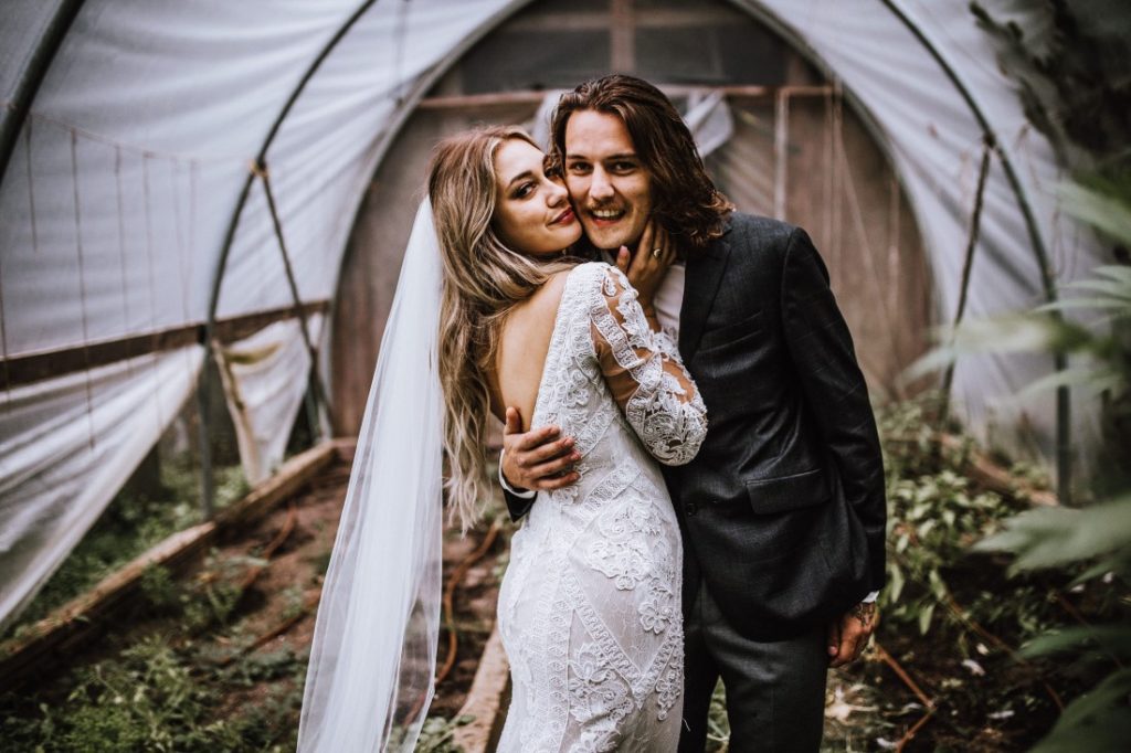 A Farm Table Wedding couple smile under tent on their wedding day