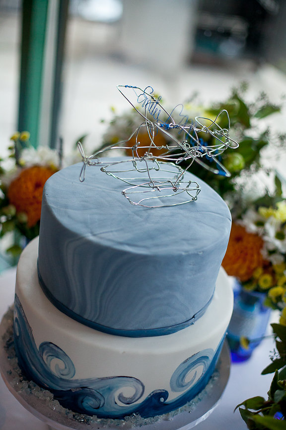 Blue wedding cake with orange and white gerbera daises