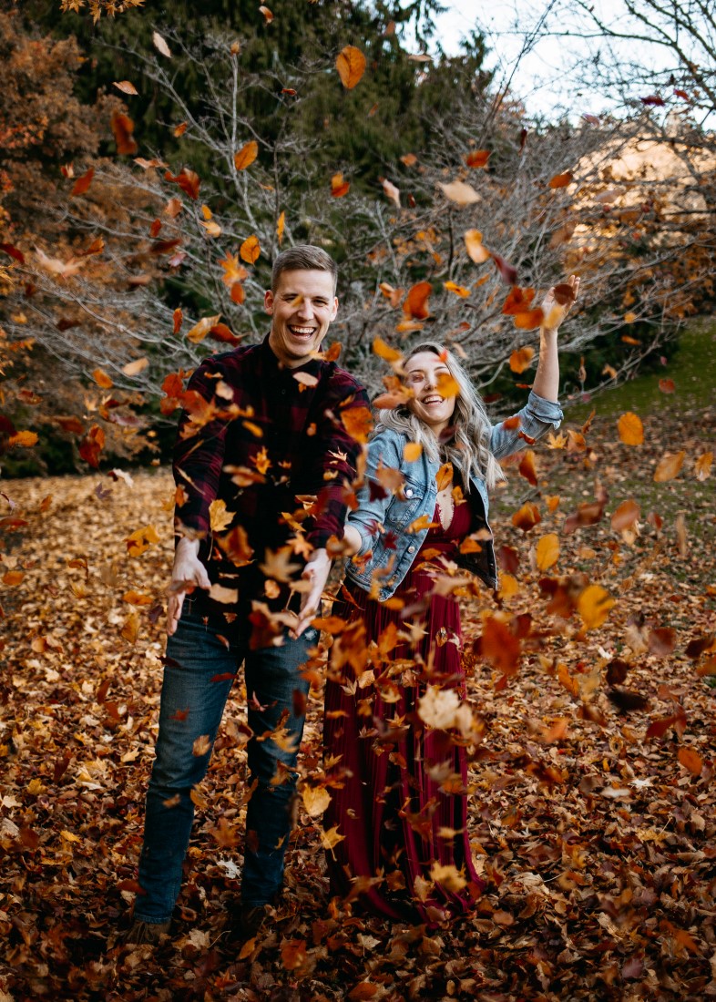 Autumn Engagement Session couple throw fall leaves in the air at Hatley Castle