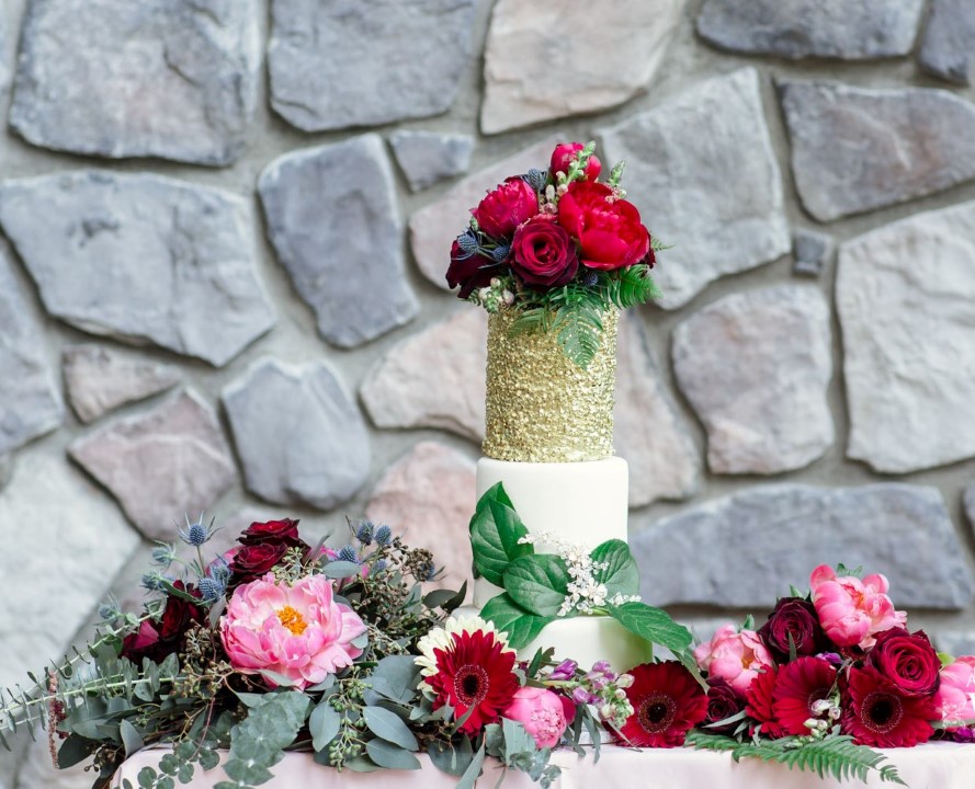 Gold sparkle thee tiered wedding cake with red and pink peonies by Thrifty Foods