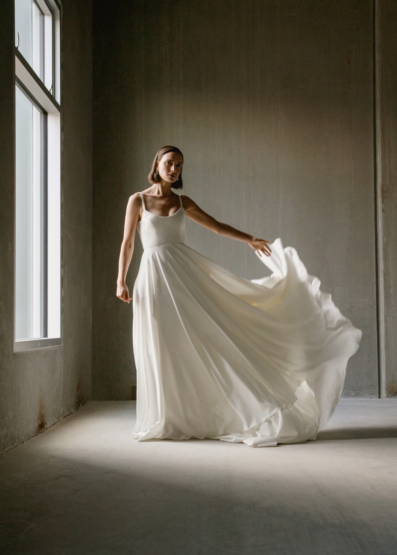 Aesling bride holds out the skirt of her minimalist 2021 collection gown in Vancouver