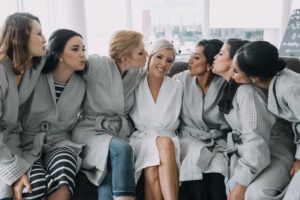 Bride and wedding party hug while getting ready with style in Vancouver