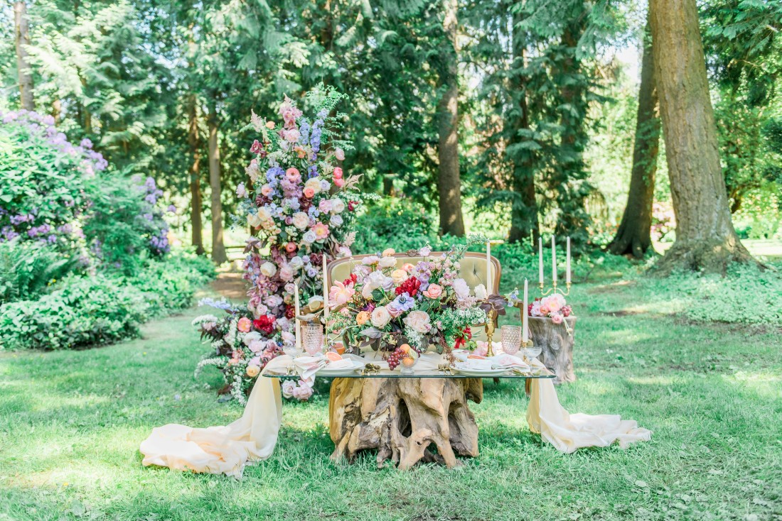 Garden of Eden Wedding Inspiration table filled with fabric, flowers and candlesticks in Vancouver Park