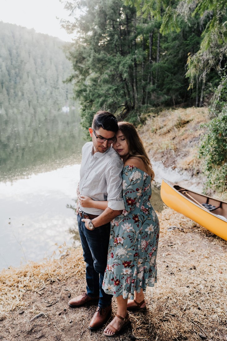 Engaged Couple stands in front of canoe by lake on Vancouver Island