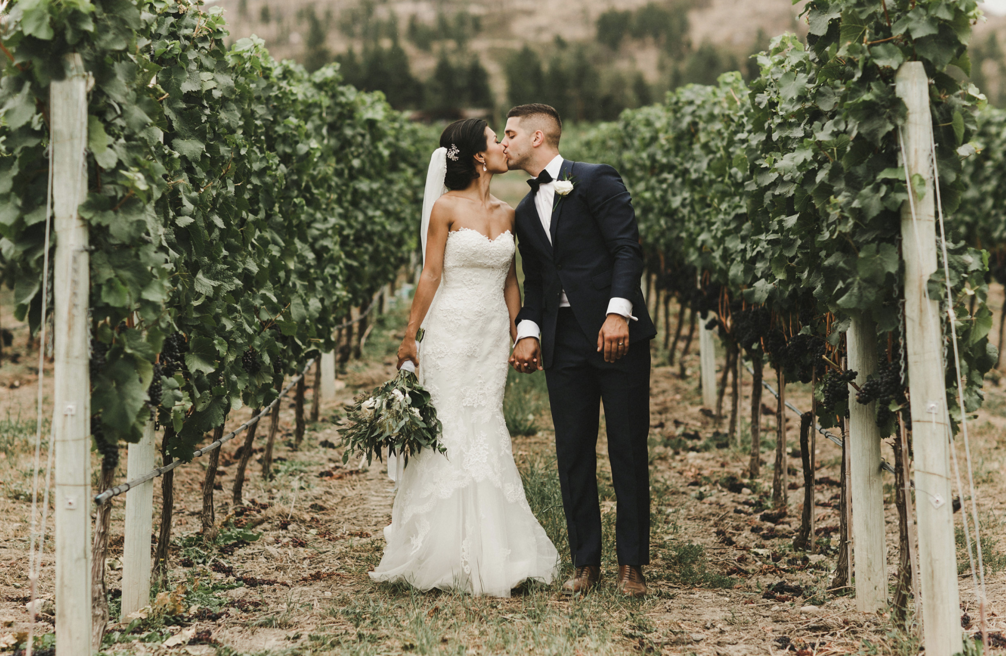 Top 10 Reasons Okanagan Destination wedding couple share a kiss in vineyard
