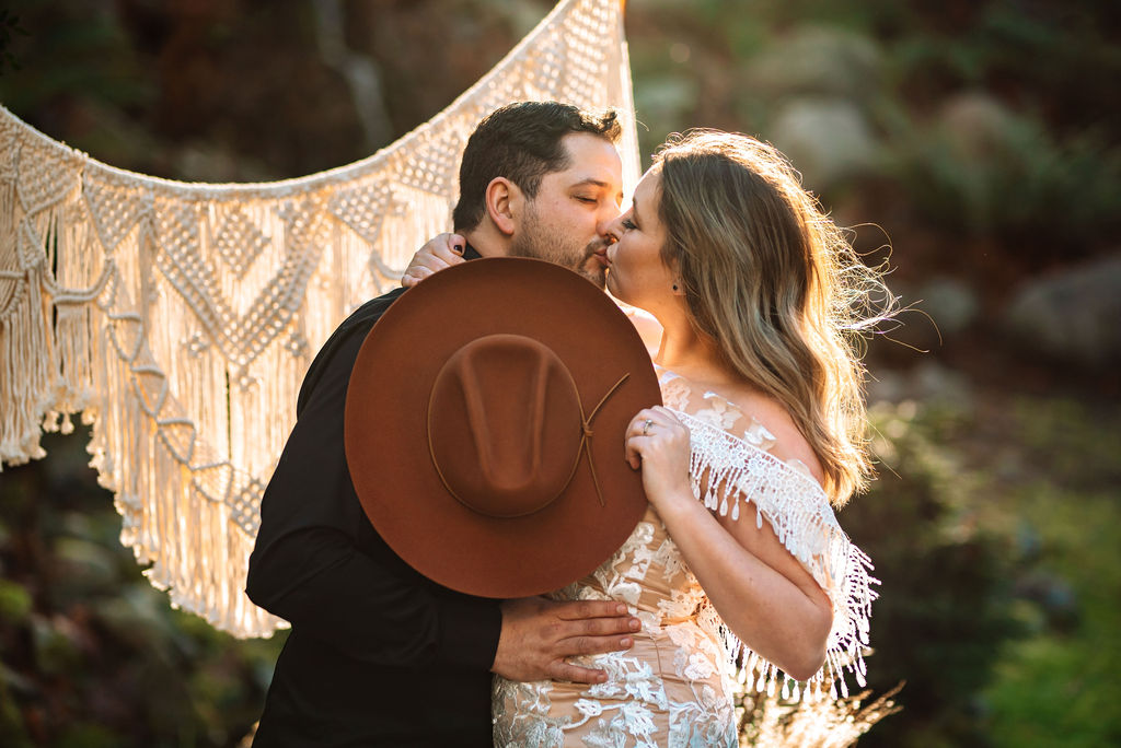 Newlyweds kiss behind brown velvet hat by Shop West Von Vancouver Island