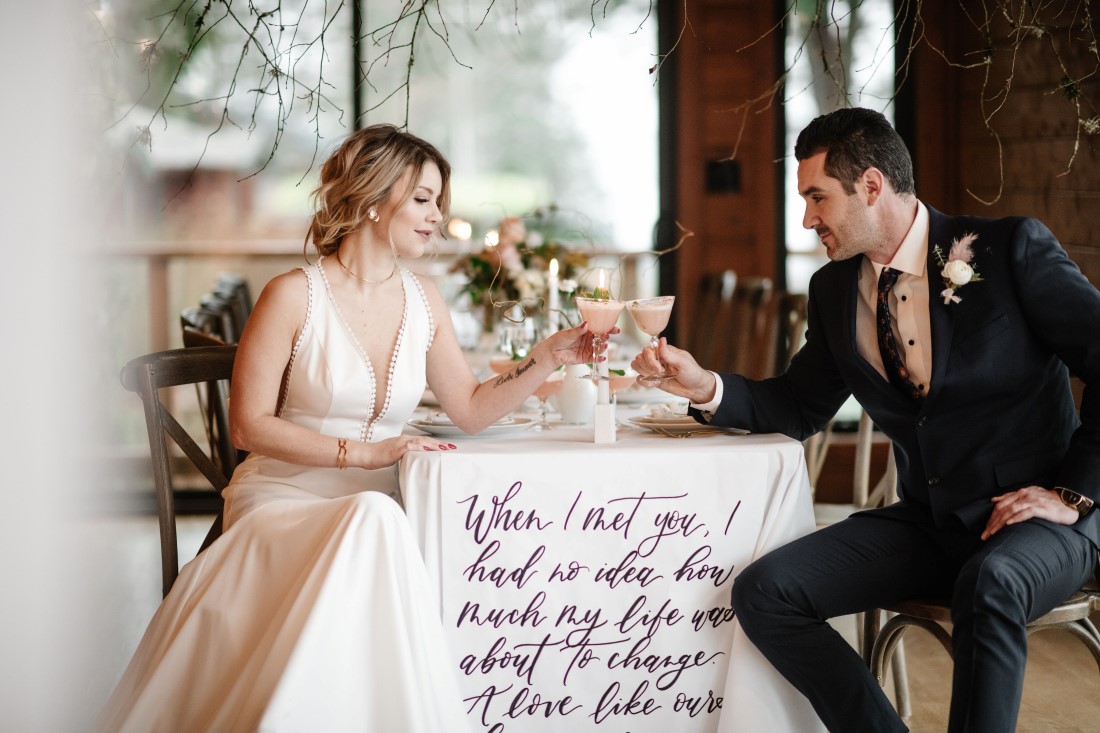 Love Letters at Dolphin's Resort newlyweds drink champagne in front of calligraphy linen