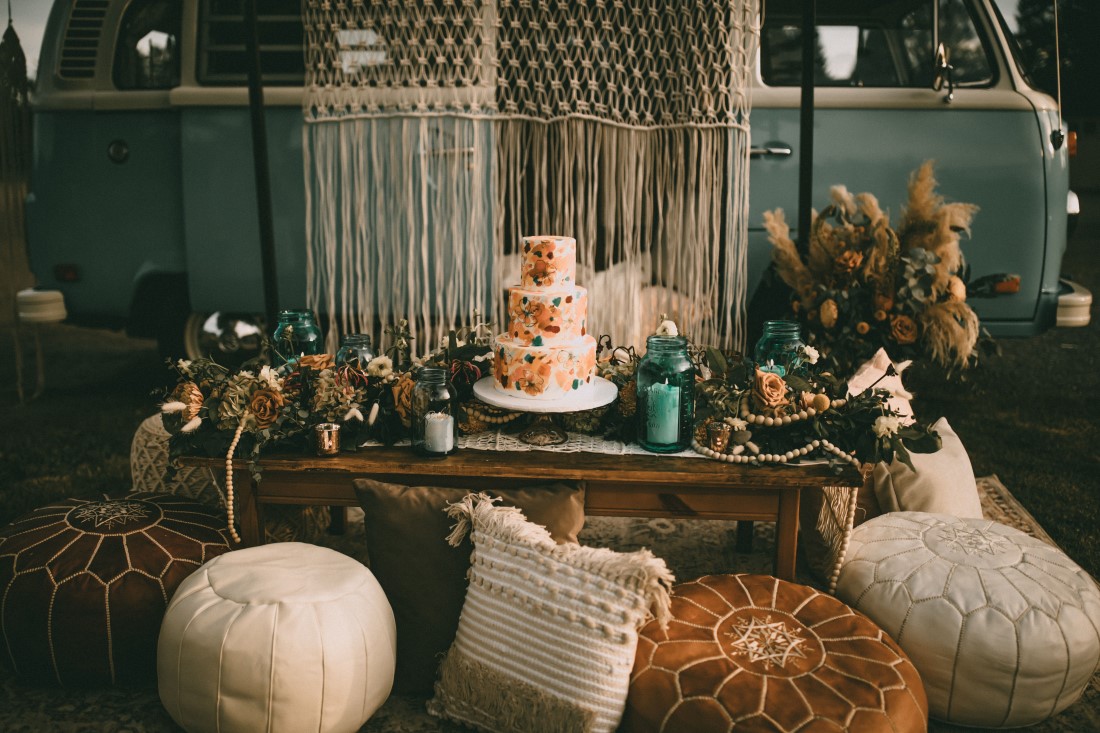 bridal cake on wood table surrounded by macrame pillows and rugs