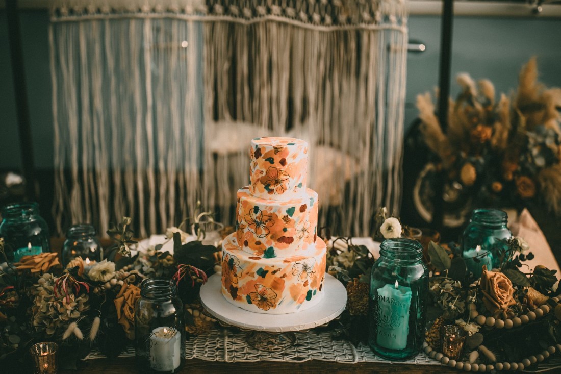 Wedding Cake sits in front of macrame backdrop by Casandra Cake Co Vancouver