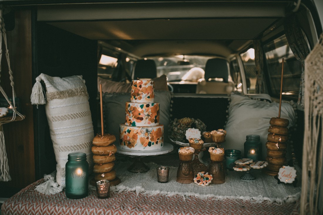 peach and blue three tier wedding cake with donuts and cupcakes in back of VW van