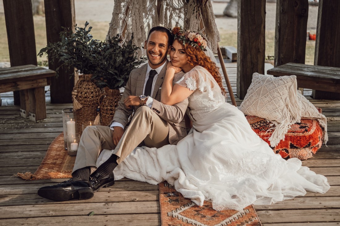 Bride and groom cuddle in front of boho teepee