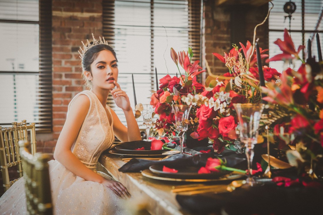 Bride at wooden table with black plates and orange and red floral Vancouver