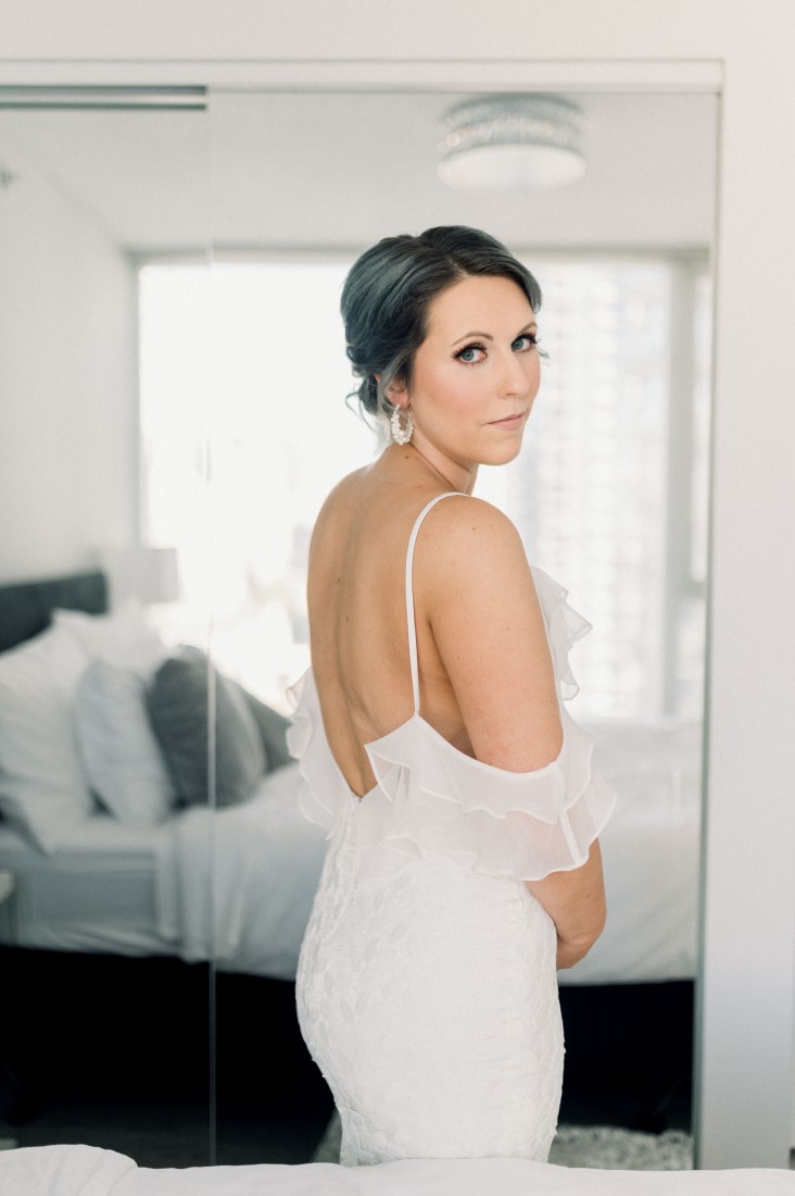 Bride looks at camera in off the should wedding gown