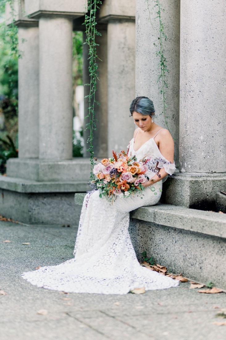 Vancouver bride sits with bouquet of peach and burgundy flowers