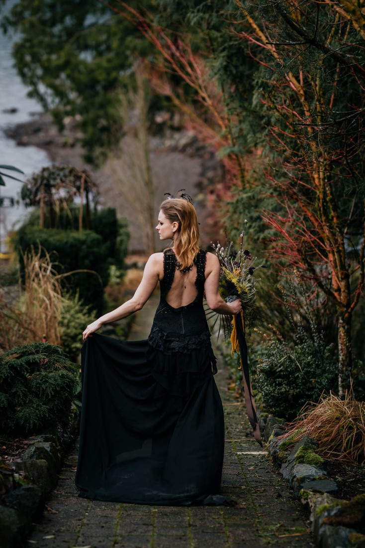 Bride in black gown walks down wilderness path