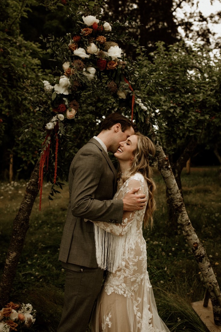 Bride and groom kiss in front of the tree at Keating Farm Vancouver Island