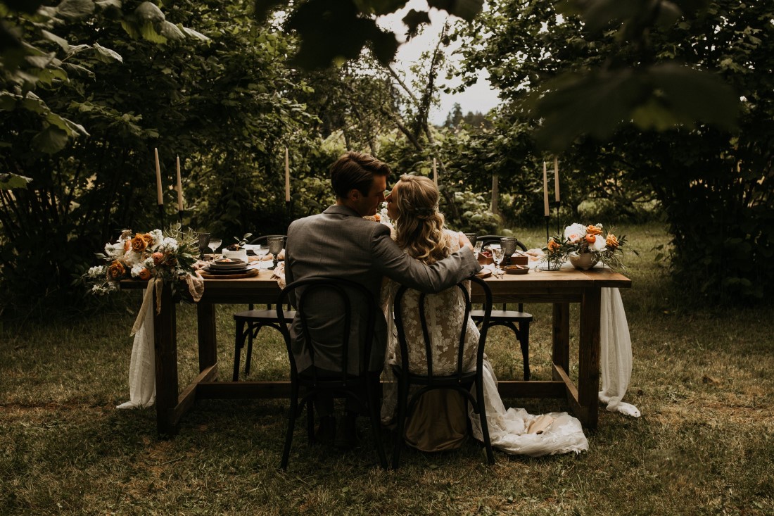 Newlyweds sit at outdoor farm table at Keating Farm Vancouver Island