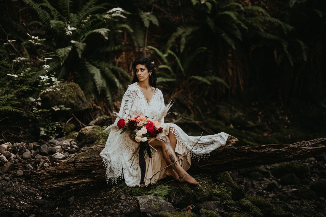 Bride sits in ferns in a lace dress