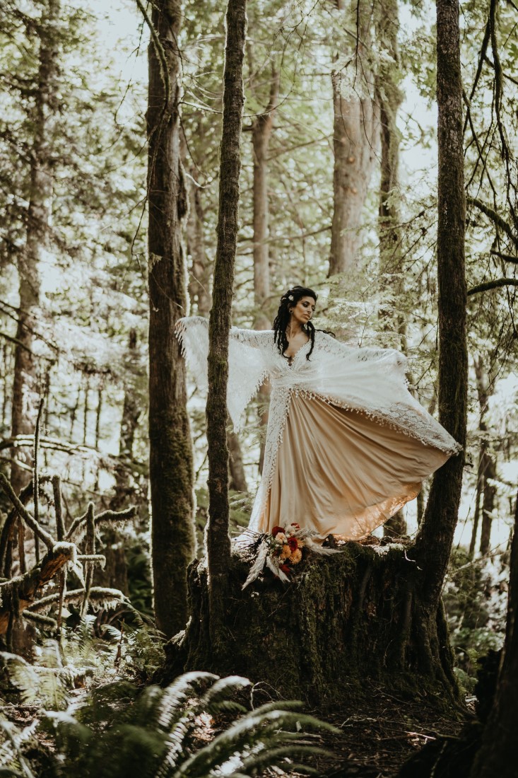 Whimsical & Woodsy bride stands on tree stump in the forest