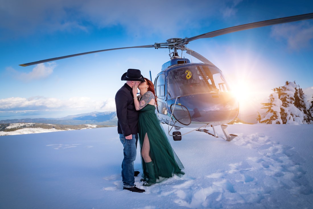Bride wears emerald green gown and groom has black cowboy hat on mountaintop