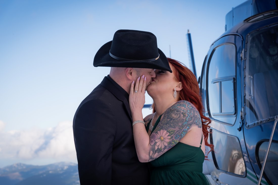 Newly engaged couple kiss by helicopter