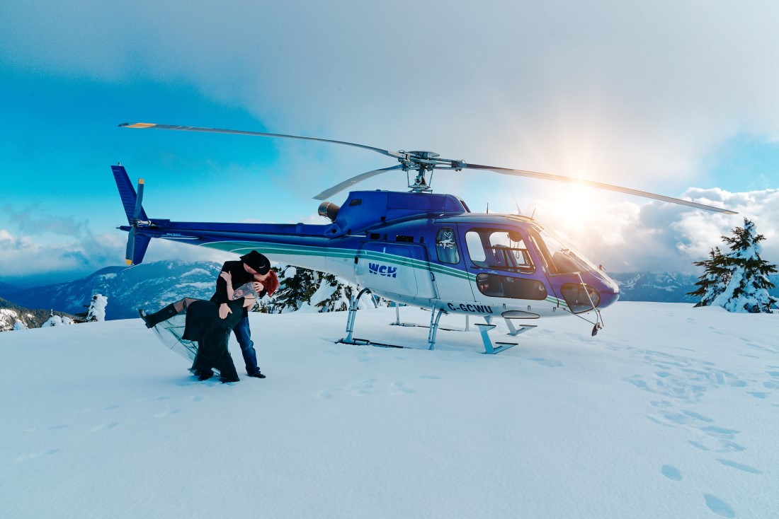Helicopter Engagement couple kisses in front of helicopter on Vancouver Island mountain