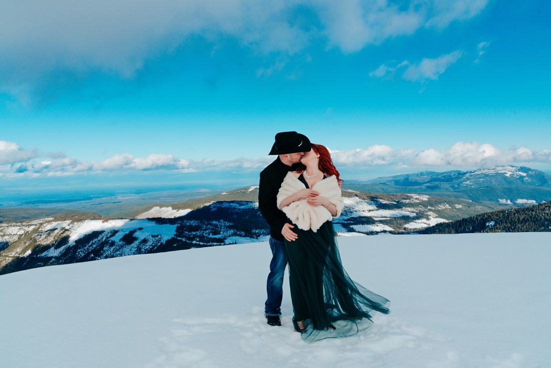 Bride wearing emerald green gown on top of snowy mountain
