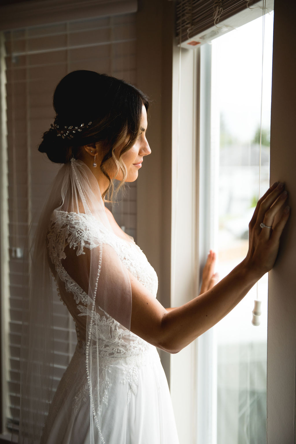 Bride looks out window in lace gown