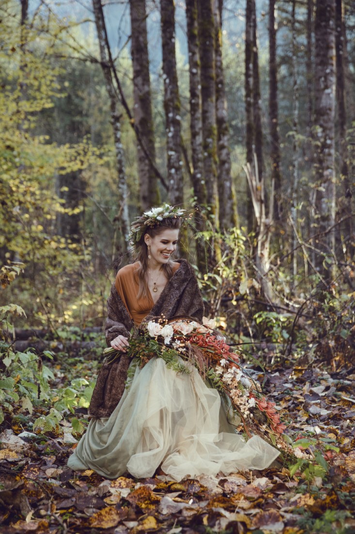 Bride in orange overskirt sits in fall Vancouver forest