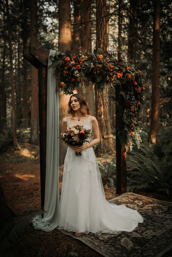 Bride in front of wedding arch in the forest 