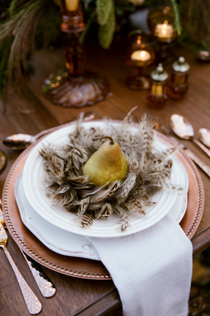 Pear and feathers sit in white plate on wedding reception table