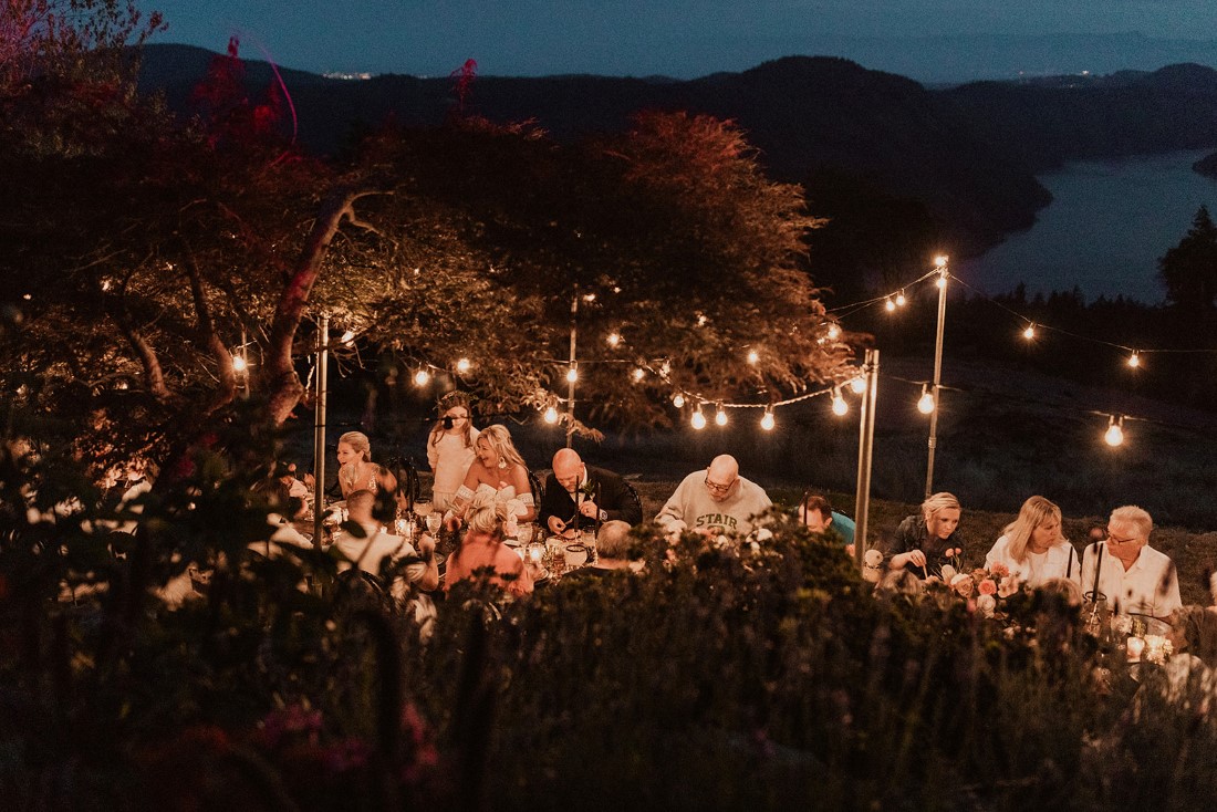 Guests eat and drink at nighttime outdoor reception table