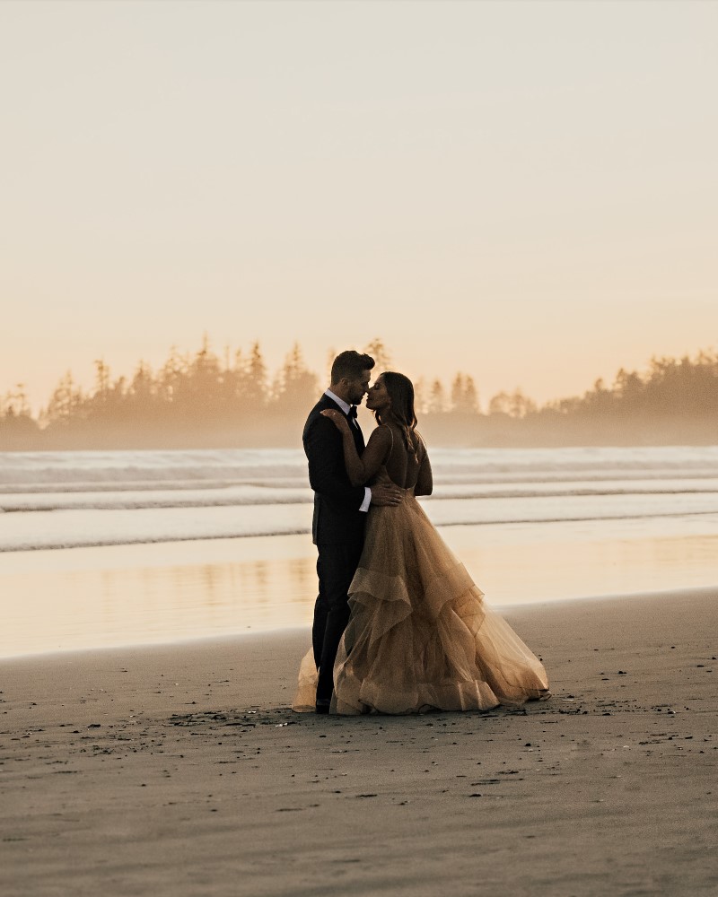 Couple on Tofino beach as sunset and mist surround them