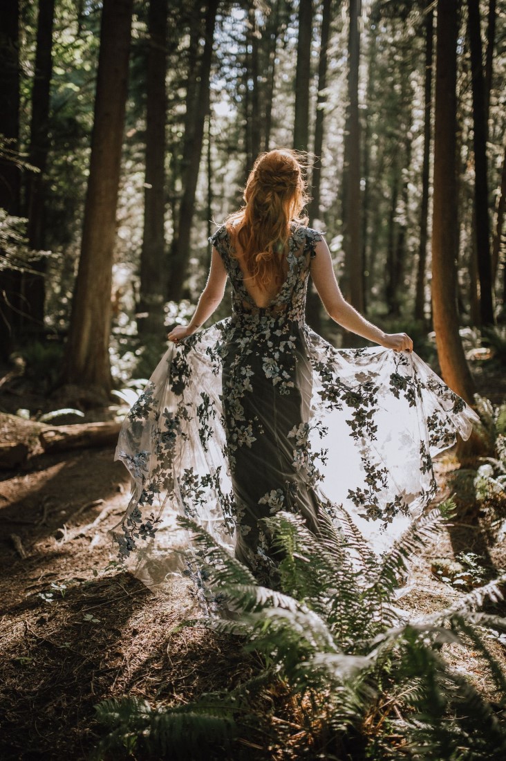Into the Woods Bride walks through sun with black lace gown by Riske Photography