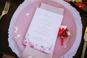 White Wedding Menue with pink flowers on pink dish setting