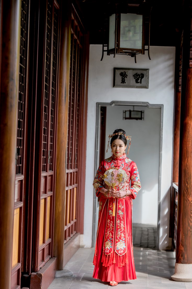 Bride walks along panelled wall in red good luck dress